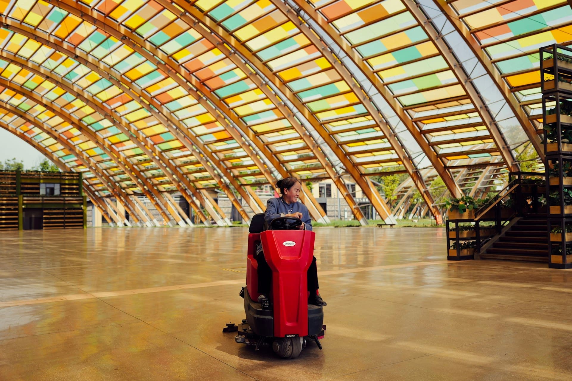 A technician driving a floor machine across a large shiny hall