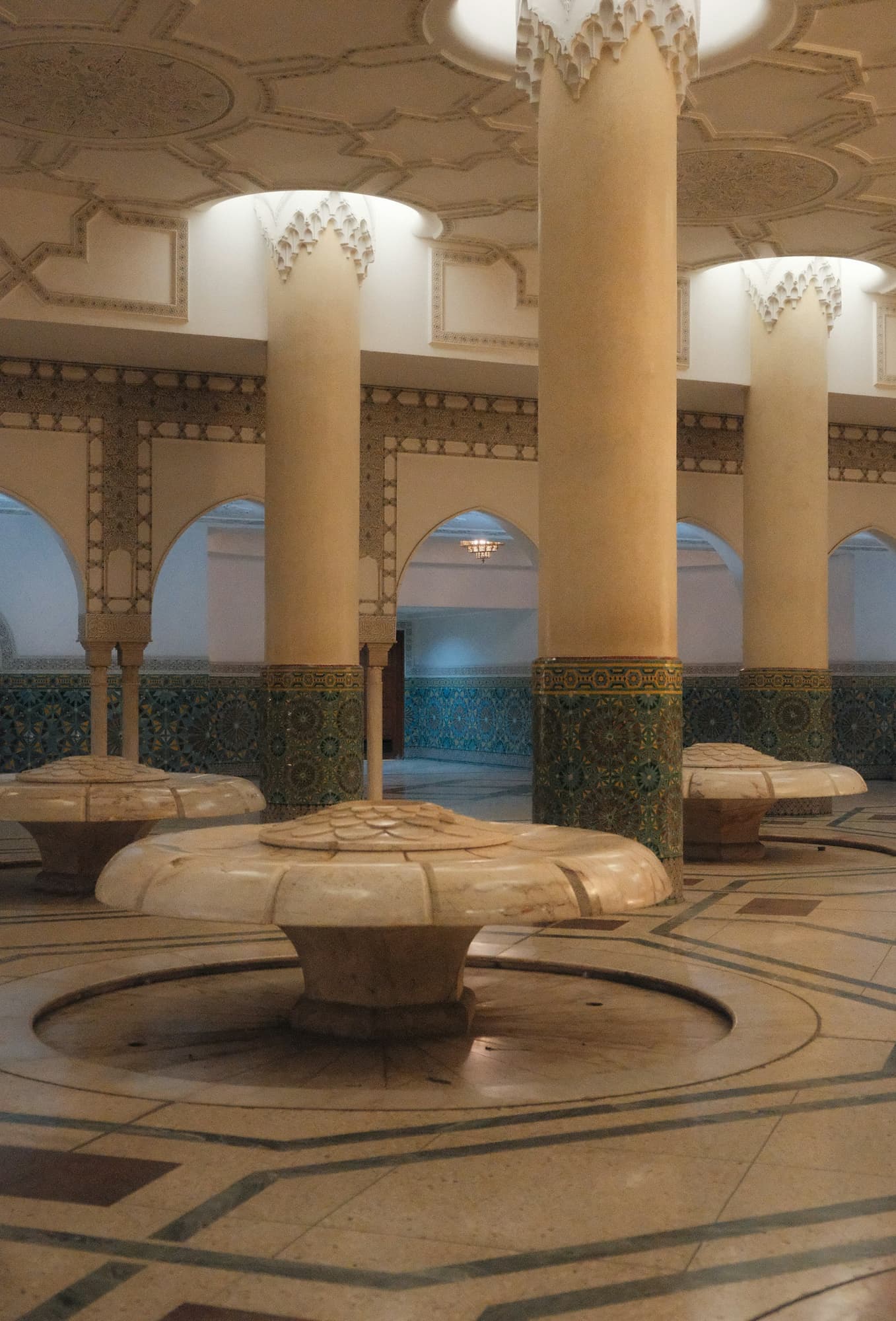 Inside a marble hammam: columns, fountains and a patterned marble floor